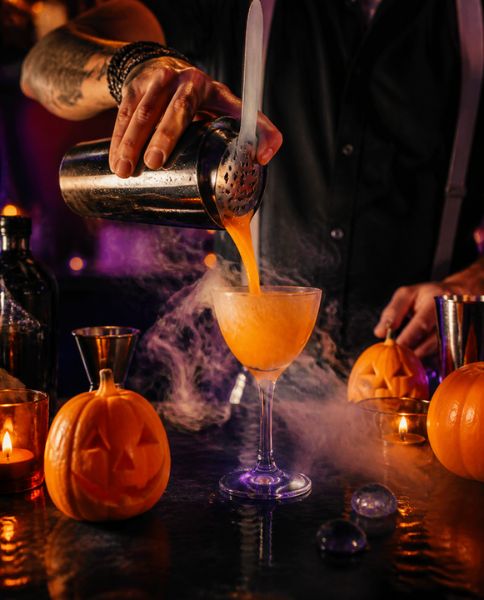 Bartender pouring an orange cocktail through smoke